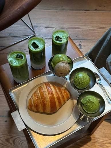 Tres matchas helados, un cruasán y helados para compartir sobre una mesa de café.